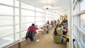 Students sit and study on laptops along sky bridge hallway of Livingston Student Center